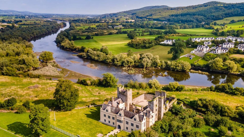 River winding through lush countryside and villages on Ireland’s Blueways, with rolling hills beyond.