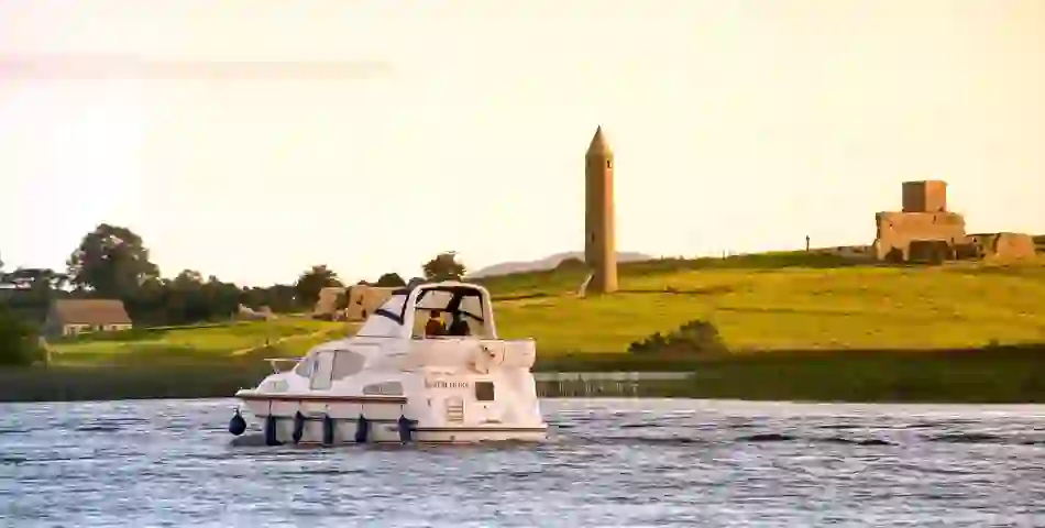 Cruiser on Lower Lough Erne passing Devenish Island’s round tower and monastic ruins.