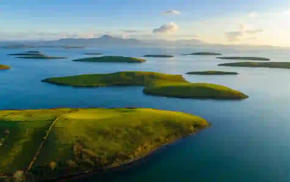 Aerial view of Clew Bay in County Mayo with green drumlin islands dotting the blue ocean and Croagh Patrick in distance.