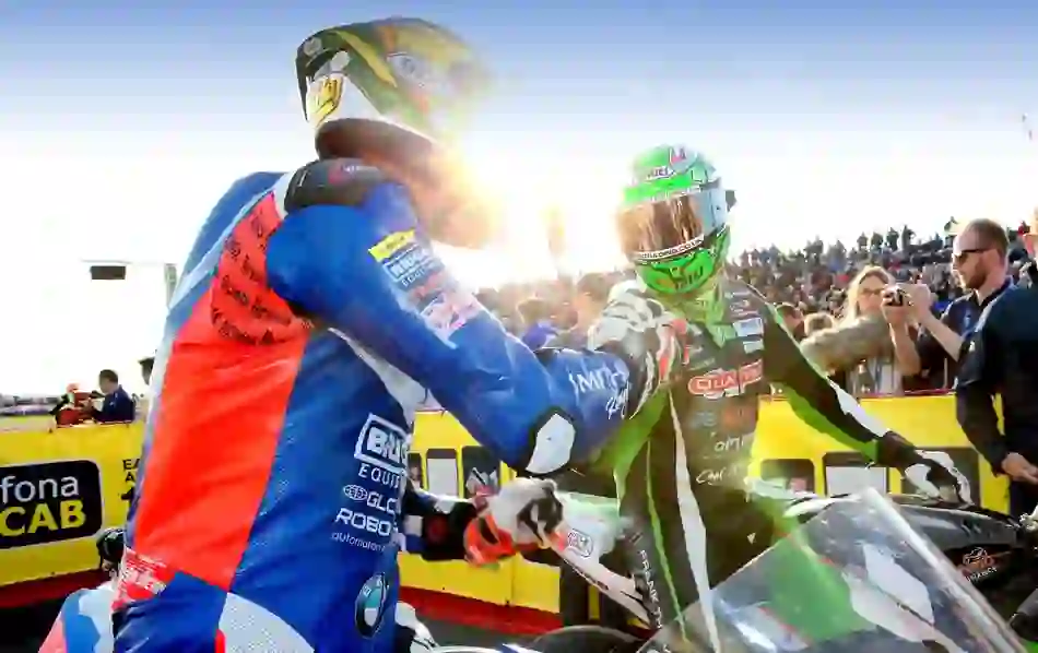Two motorcycle racers in full gear congratulating each other at the finish line of the North West 200, Portrush.