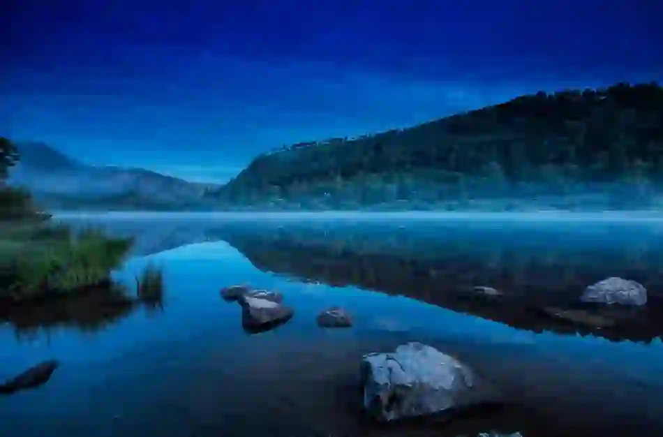 Misty morning reflection of forested hills on Upper Lake, Glendalough, County Wicklow.
