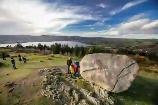 Family standing at Cloughmore Stone with panoramic views over Carlingford Lough and Mourne Mountains.