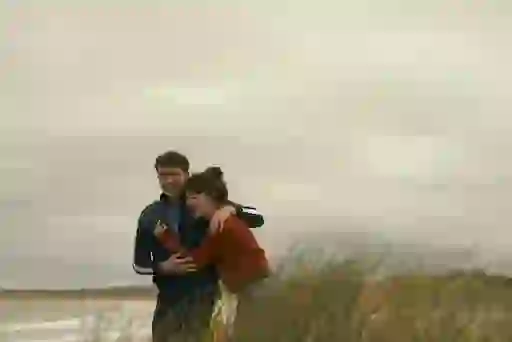 Marianne and Connell laugh together on a windswept Sligo beach.