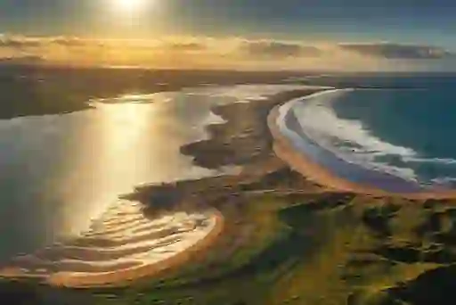 Aerial view of Streedagh Beach’s sandy curve and rolling waves under the evening sun.