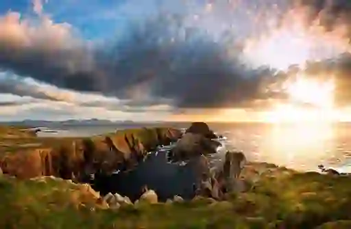 Cliffs at Malin Head lit by sunset glow under a dramatic sky on Ireland’s Wild Atlantic Way in Donegal.