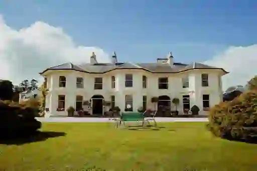 Rathmullan House with bay windows and green lawn, surrounded by hedging and flowerpots in Donegal.