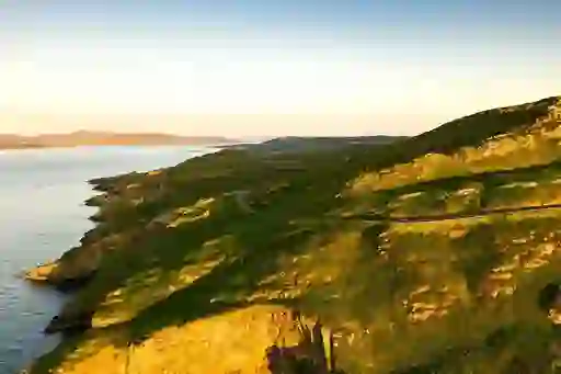 Coastal road winding past cliffs and headlands at sunset in Portsalon, County Donegal.