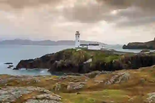 Fanad Head Lighthouse on a rocky promontory overlooking the Atlantic Ocean under moody Donegal skies.