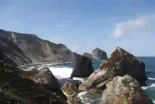 Jagged sea stacks rise dramatically from Glenlough Bay’s Atlantic waters, surrounded by rugged cliffs and crashing waves.