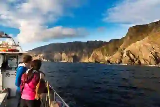 Couple on a boat tour gaze at the towering Slieve League cliffs, among the highest sea cliffs in Europe, in Donegal.