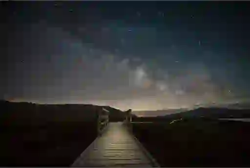 Wooden boardwalk leading into dark skies filled with stars in County Mayo’s Wild Nephin park.