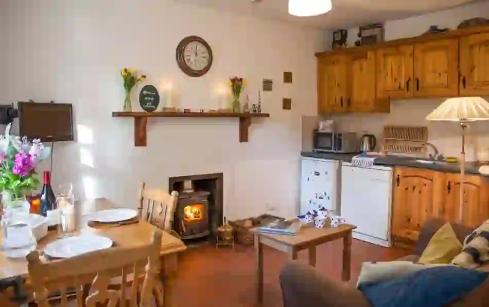 Cosy self-catering kitchen with pine cabinets, wood stove and dining table in Mr McGregor's Cottage, County Tyrone.