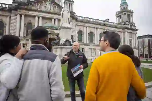 Guide leading a walking tour outside Belfast City Hall in Belfast city centre.