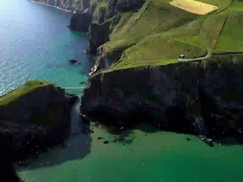 Aerial view of Carrick-a-Rede Rope Bridge stretching across cliffs above turquoise waters in County Antrim.