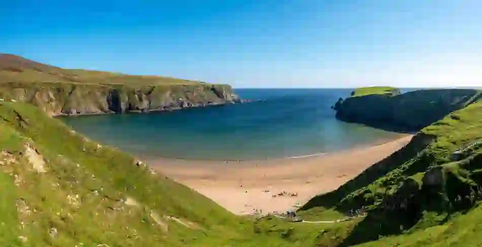 Horseshoe-shaped Silver Strand with golden sand and dramatic cliffs, County Donegal.