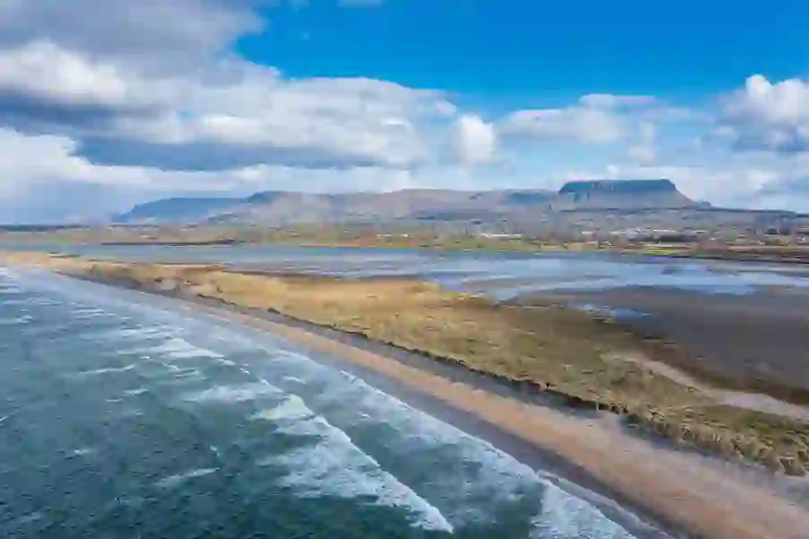 Waves breaking along Strandhill Beach with sandy dunes, tidal flats, and Ben Bulben mountain in the distance.