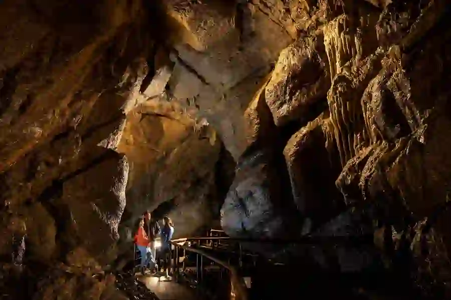 Three visitors stand on a walkway deep underground in the Marble Arch Caves in County Fermanagh.