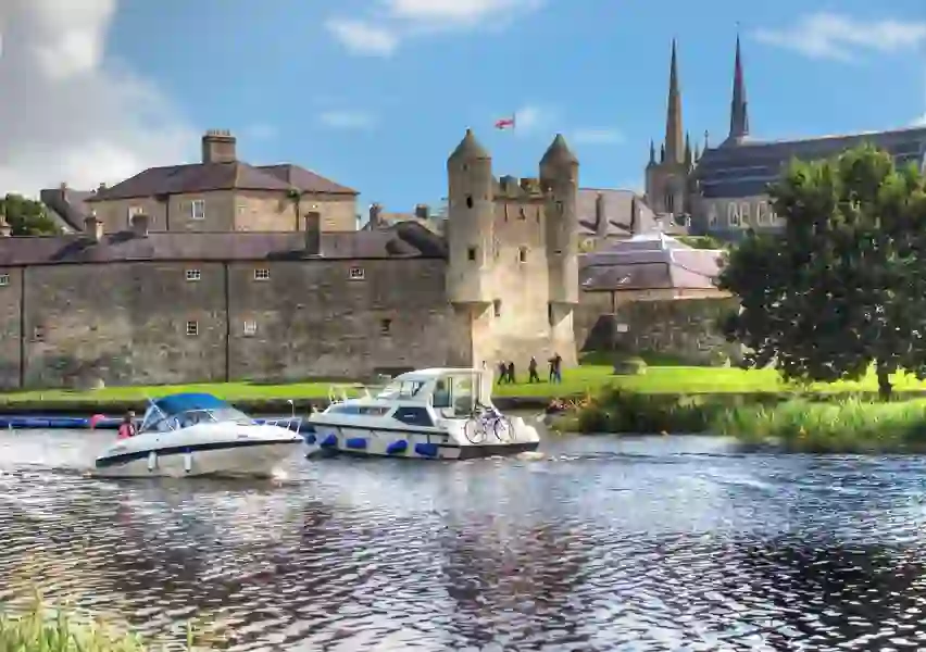 Two boats pass by one another on the River Erne with Enniskillen town in the background.