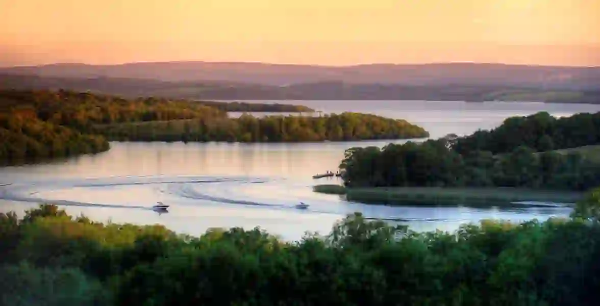 Two boats cruising through the tranquil Fermanagh Lakelands at sunset.
