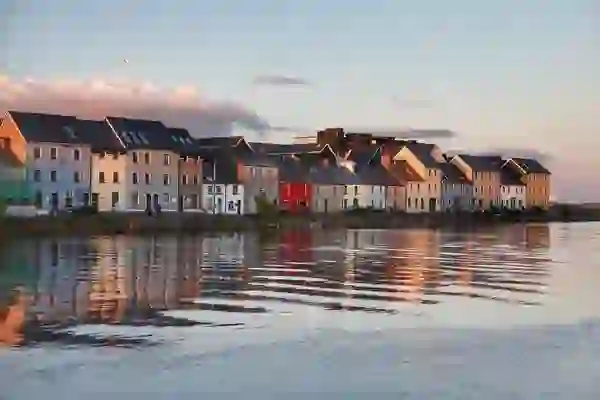 Colourful houses along The Claddagh reflected in the River Corrib at sunset in Galway City.