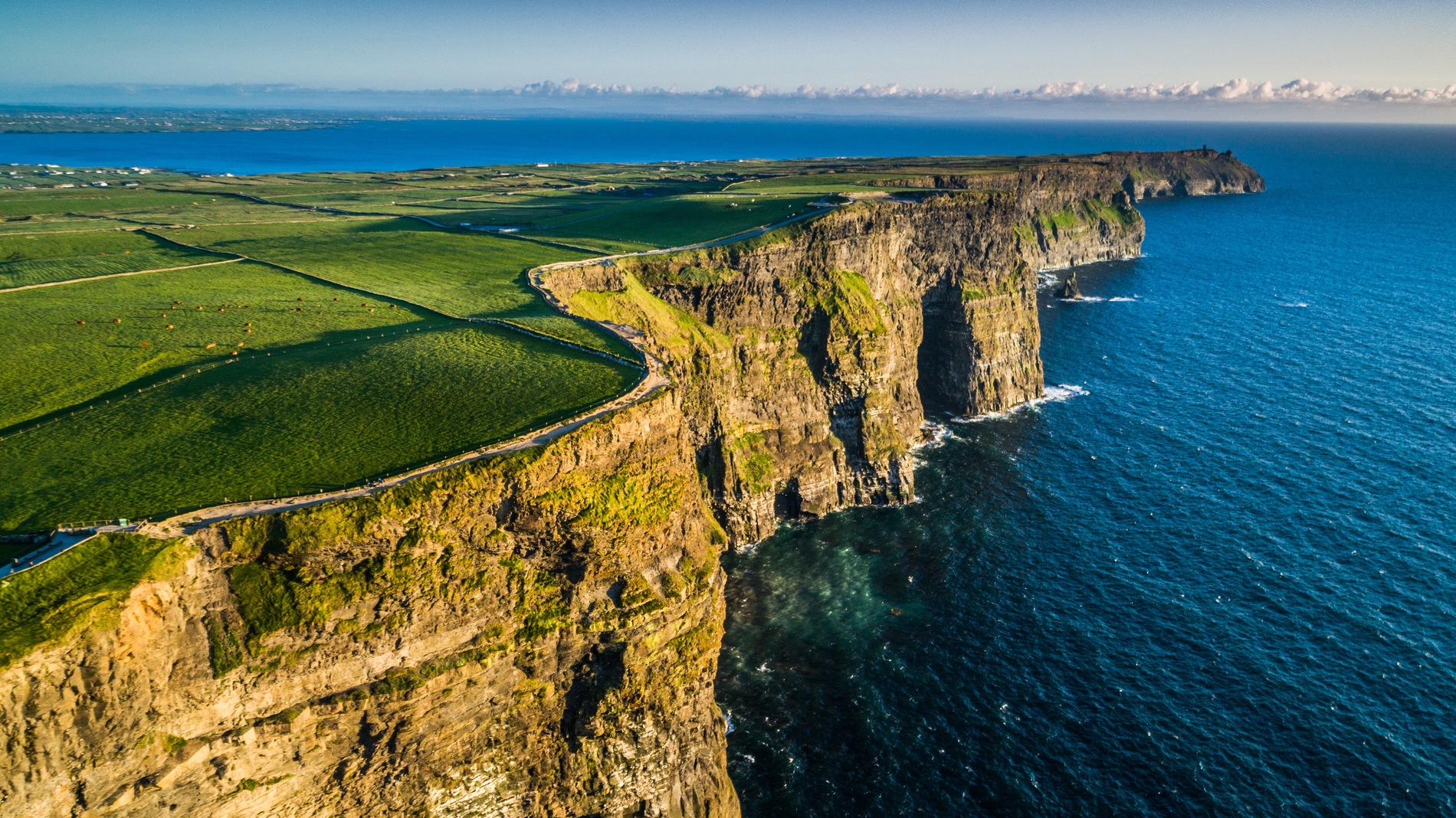 Aerial view of the Cliffs of Moher overlooking the Atlantic Ocean in County Clare, with fields stretching inland.