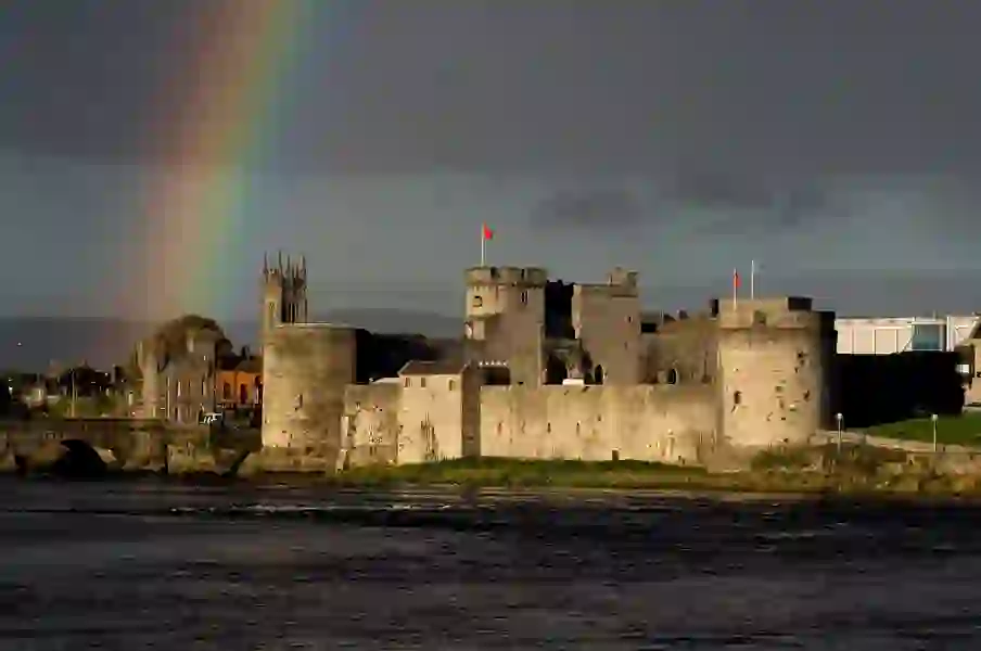 Rainbow arches over King John's Castle beside the River Shannon in Limerick city at sunset.