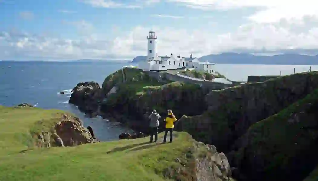 Two people taking photos at Fanad Head Lighthouse on the Wild Atlantic Way, County Donegal.