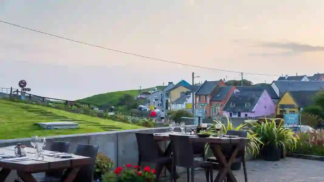 Outdoor dining area with set tables overlooking a colourful coastal street in Doolin, County Clare.