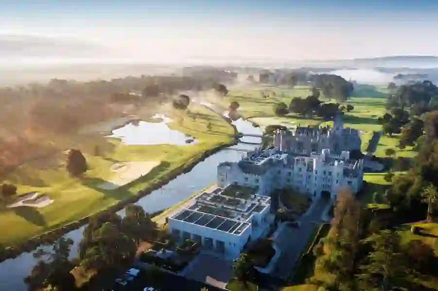 Aerial view of Adare Manor in County Limerick, a luxury castle estate with golf course and misty sunrise.