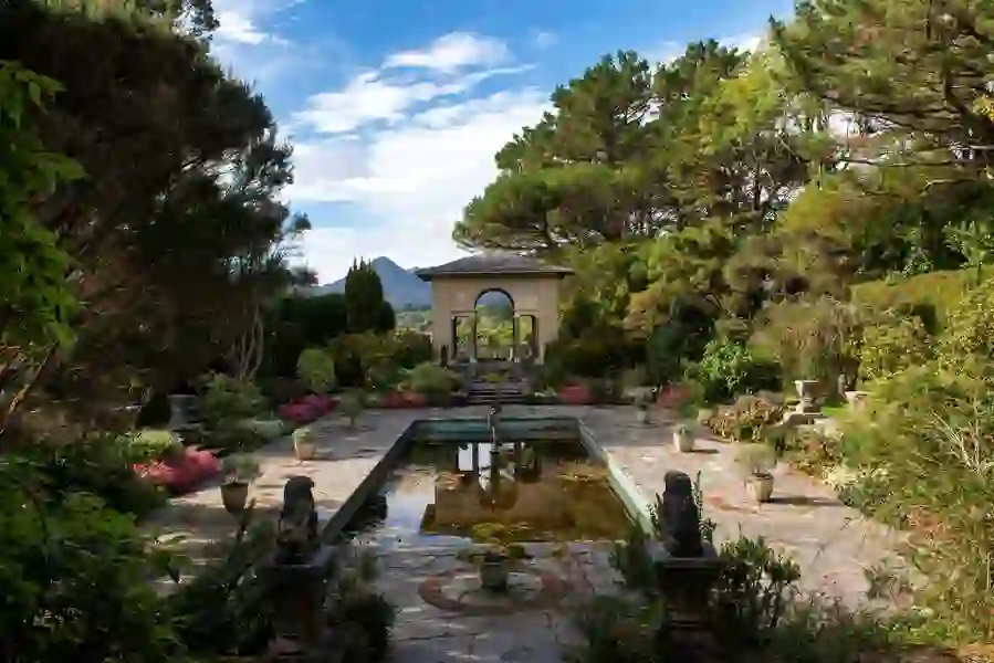 Ornamental pond garden with archway, flowers, and mountain backdrop at Garnish Island, County Cork.