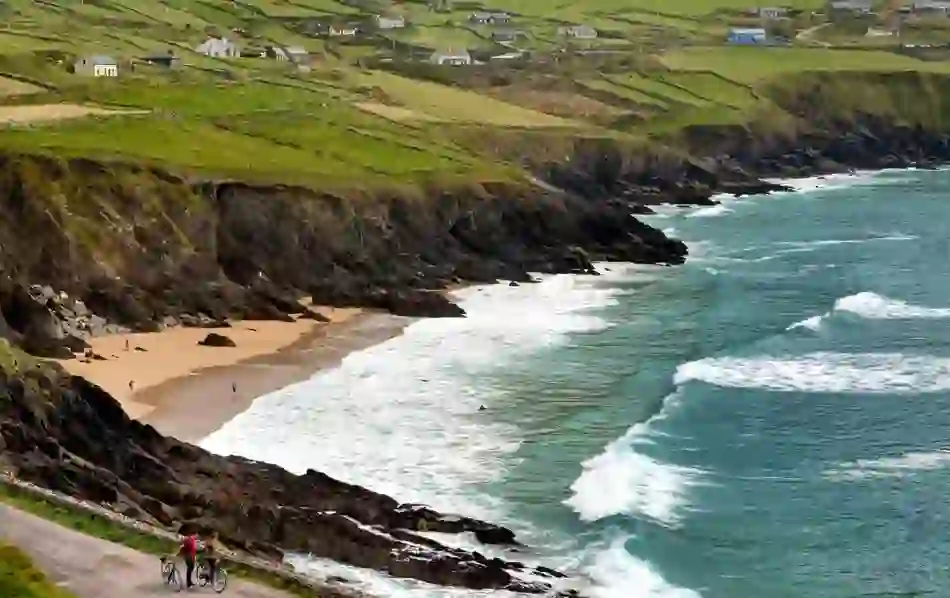 Waves lapping against the shore at Coumeenoole Beach on the Dingle Peninsula in County Kerry, with cottages perched on cliffs.