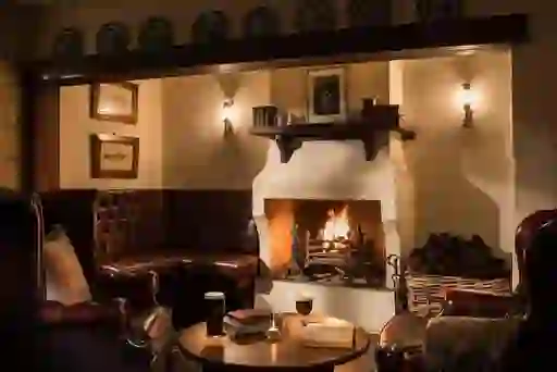 Traditional pub snug with leather seating, books and drinks by the fireplace at Bushmills Inn, County Antrim.