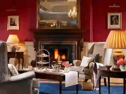 Opulent drawing room with a lit fire, chandeliers and afternoon tea setting at Knockranny House Hotel and Spa, County Mayo.