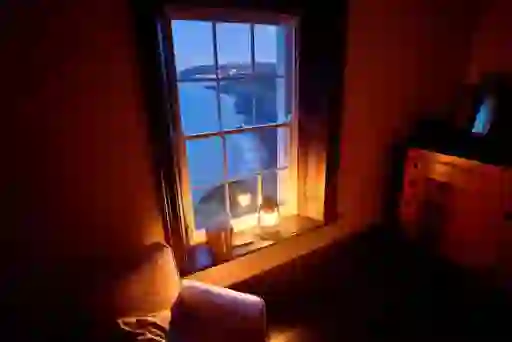 Cosy room with a lantern-lit window overlooking the Irish coastline at Blackhead Lightkeeper’s House, County Antrim.