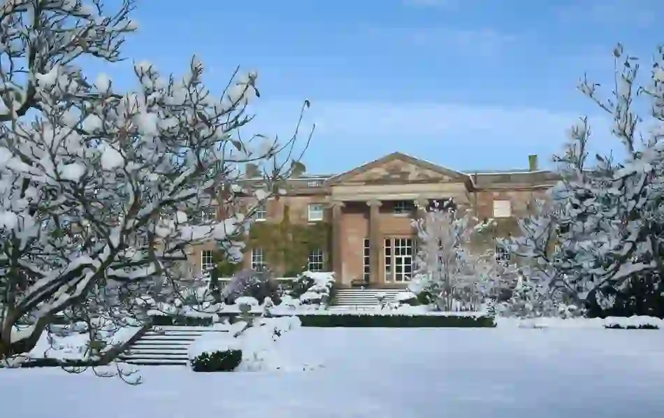 Hillsborough Castle stands serene behind snow-laden trees in a peaceful garden setting.