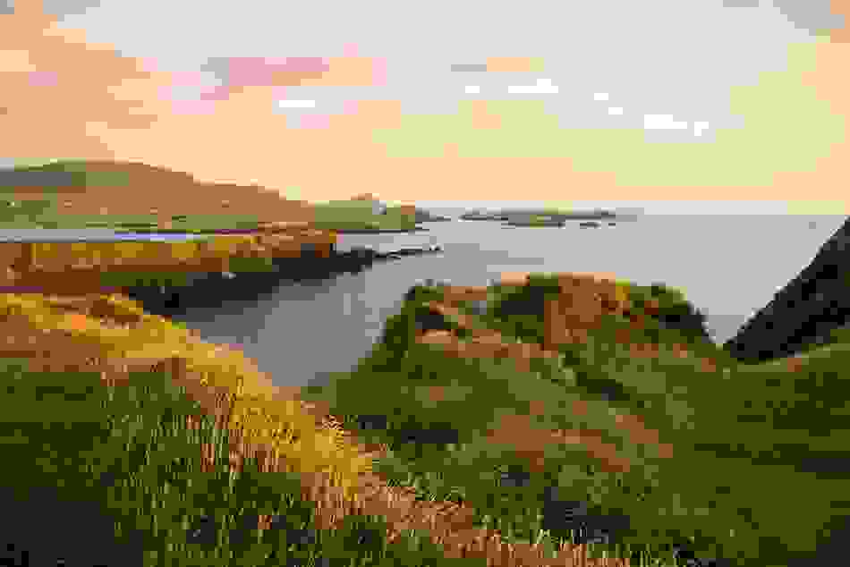 Scenic view of Slea Head Drive cliffs and Atlantic Ocean at sunset on the Dingle Peninsula.