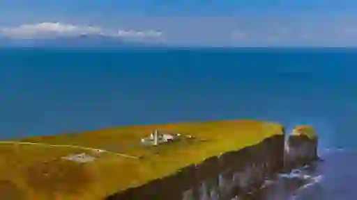 Loop Head Lighthouse complex on grassy headland above steep sea cliffs, surrounded by ocean views in County Clare.