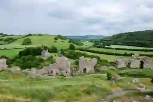 Ruins of the Rock of Dunamase overlooking rolling green countryside and a distant stone chapel in County Laois.
