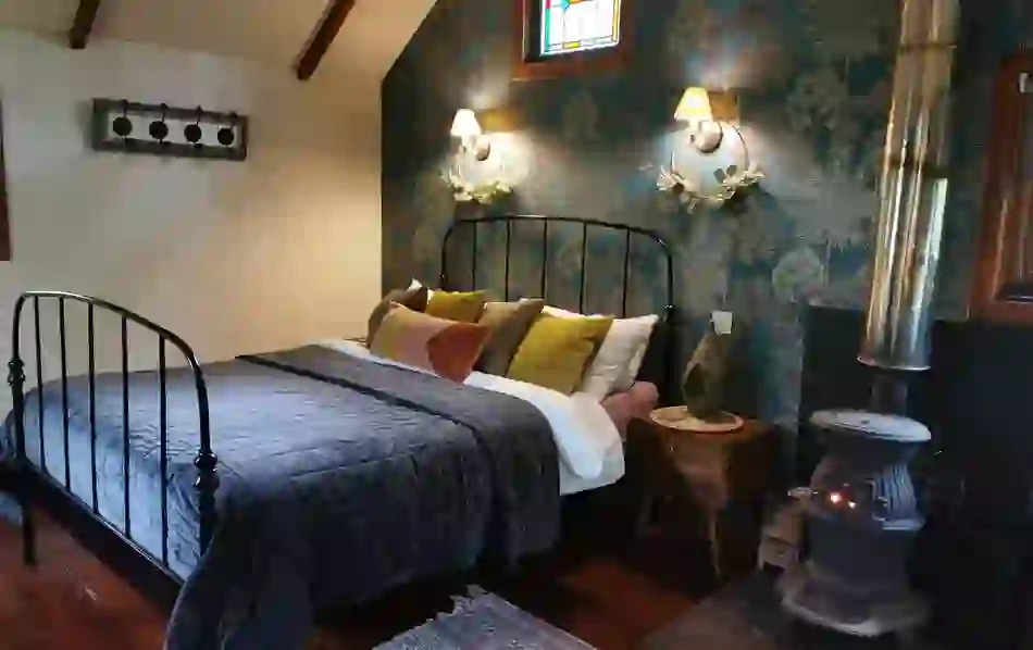 Rustic bedroom with iron bed and wood stove at Teapot Lane Glamping, County Leitrim.