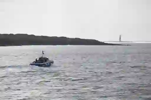 Small tour boat travels across the Atlantic in Sligo Bay, with a lighthouse visible on a distant headland.