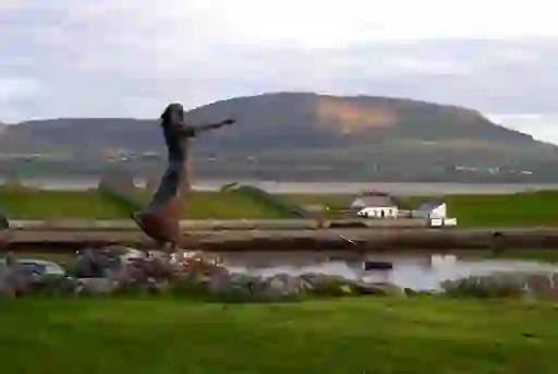 Bronze 'Waiting on Shore' sculpture overlooks the sea in Rosses Point, County Sligo, with Knocknarea in the background.