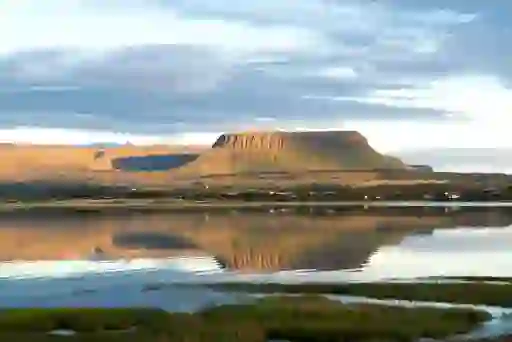 Ben Bulben’s distinctive flat-topped silhouette reflected in calm waters near Drumcliffe, County Sligo, at golden hour.