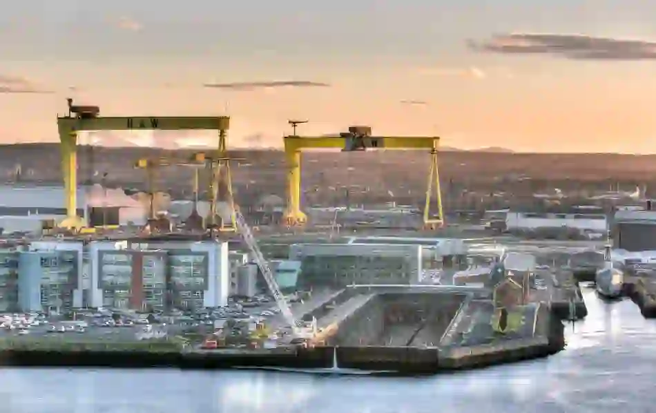 View of the Titanic dry dock and pump house at sunset, with Sampson and Goliath cranes towering above.