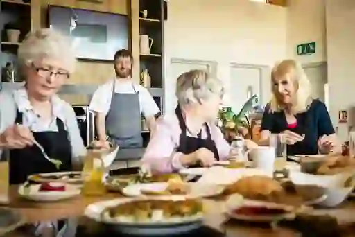 Group taking part in a cookery class at Airfield Estate in Dublin with a smiling chef leading.