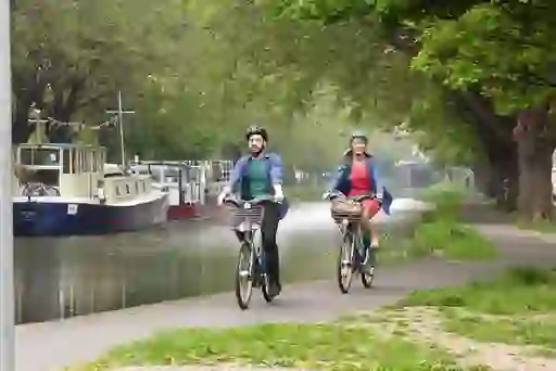 Two people cycling along Dublin’s Grand Canal with moored boats in the background.