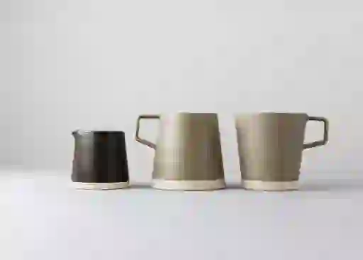 Set of three minimalist ceramic mugs and a pourer from Arran Street East on a neutral background.