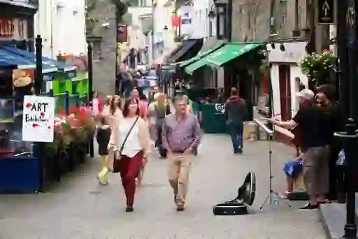 Visitors walking along a lively street with shops and musicians, County Kilkenny.