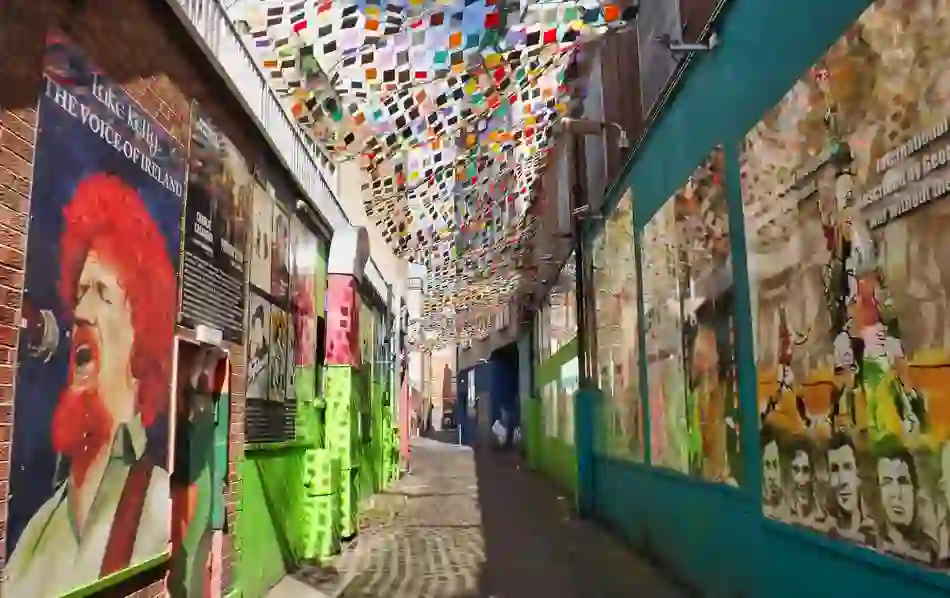 Colourful alleyway in Temple Bar with murals, posters, and a canopy of multicoloured flags.