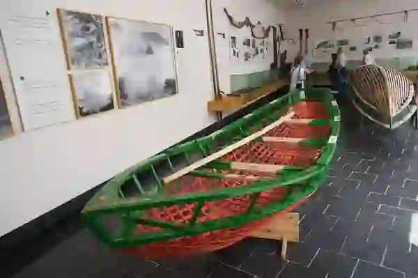 Traditional boats on display inside the Blasket Island Centre, with visitors viewing maritime exhibits and historic photos.