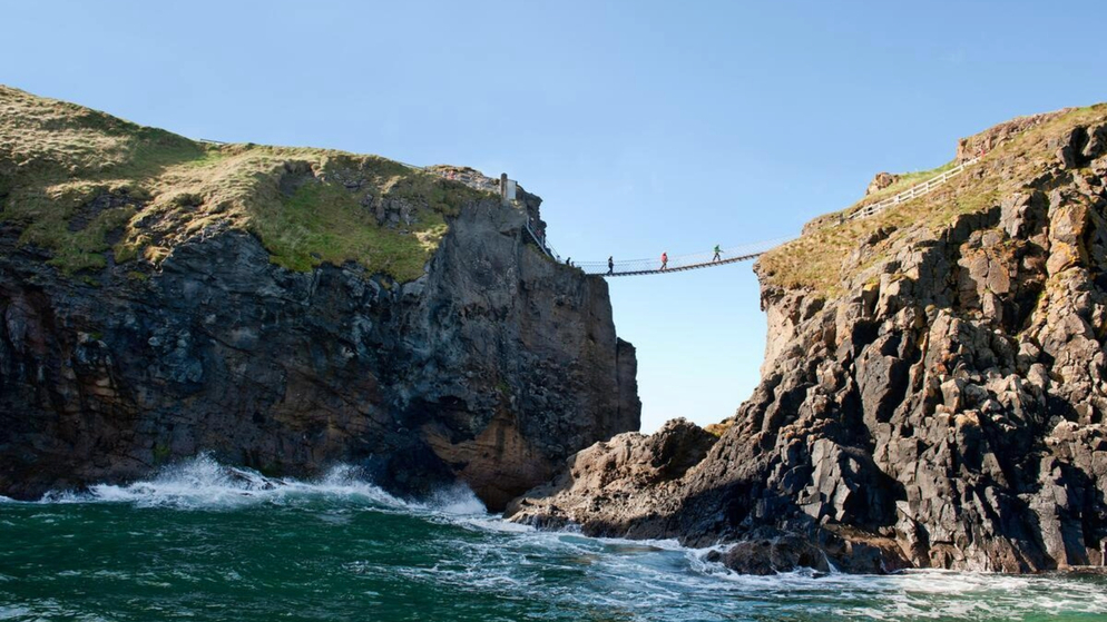 Waves crashing below Carrick-a-Rede Rope Bridge between steep basalt cliffs on the Causeway Coast.